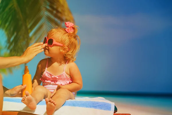 Ochrana proti slunci na pláži - použití opalovací krém krém na obličej a dcera matka — Stock fotografie