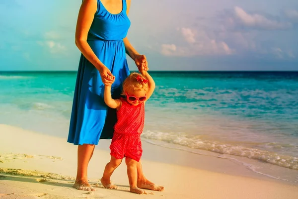 Mère et mignonne petite fille marchant sur la plage — Photo