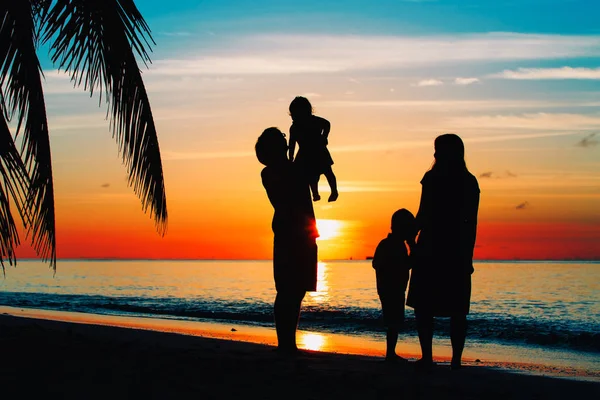 Familia feliz con dos niños juegan en la playa del atardecer — Foto de Stock