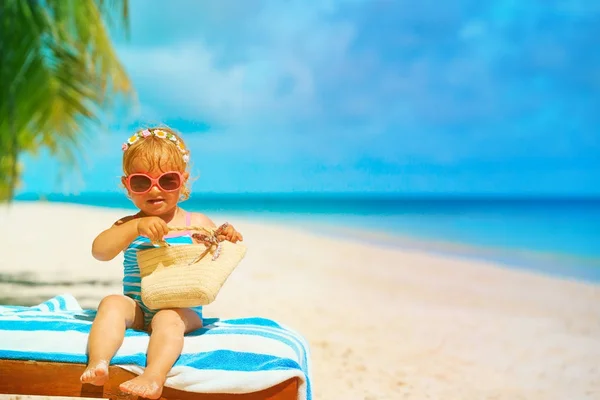 Милая маленькая девочка с сумкой расслабиться на тропическом пляже — стоковое фото