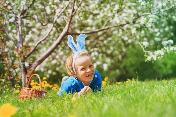 Lindo niño feliz en la caza de huevos de Pascua en primavera — Foto de Stock