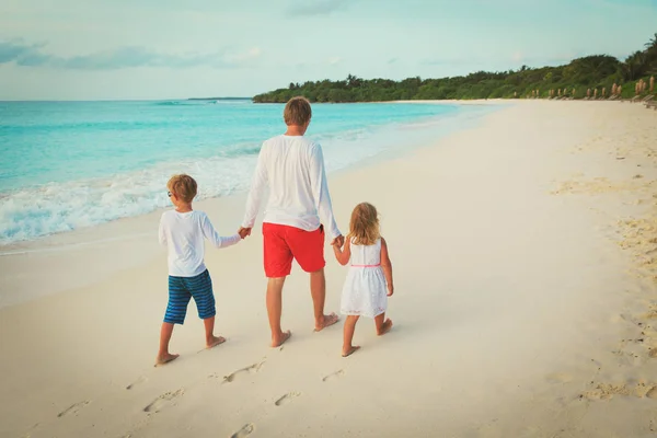 Отец и двое детей прогуливаются по пляжу — стоковое фото