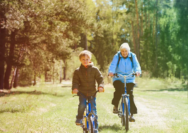 Активная старшая бабушка с внуком на велосипедах на природе — стоковое фото