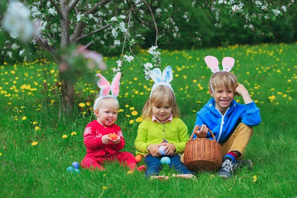 Niños felices en la caza de huevos de Pascua en primavera — Foto de Stock
