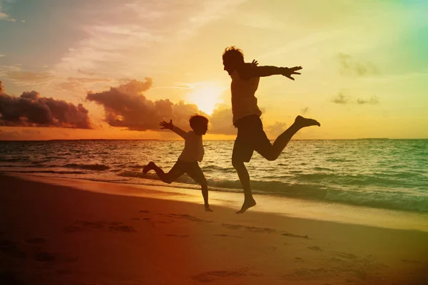 Pai e filho pequeno desfrutar de pôr do sol praia — Fotografia de Stock