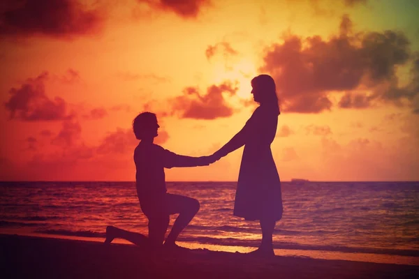 Silhueta de um jovem casal romântico na praia do pôr do sol — Fotografia de Stock