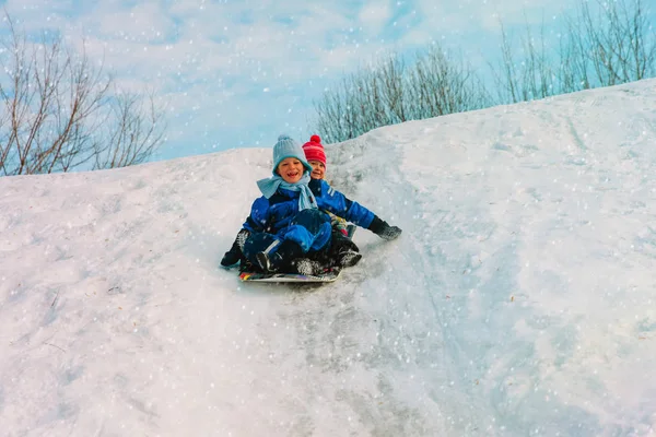 Küçük erkek ve kız çocuk kış karda slayt — Stok fotoğraf