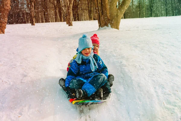 Маленький хлопчик і дівчинка ковзають взимку сніг — стокове фото