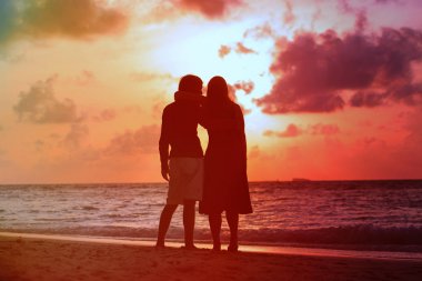 sunset beach adlı genç romantik sevgi dolu çift sarılmak