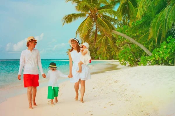 Familia feliz con dos niños caminando en la playa — Foto de Stock