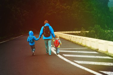 Baba ve sırt çantaları çocuklarla okula veya seyahat gitmek