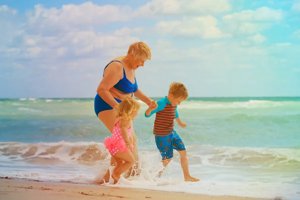 Avó feliz com crianças brincam na praia — Fotografia de Stock