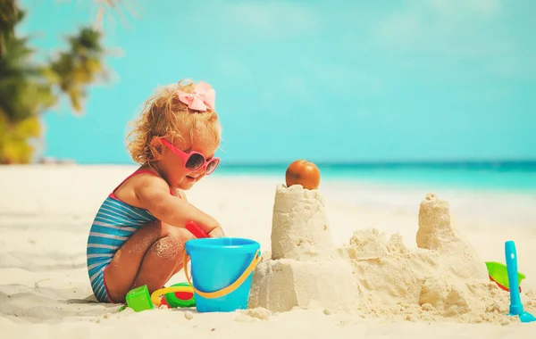 Cute little girl playing with sand on beach — Stock Photo, Image
