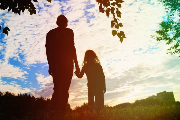 Silhueta de pai e filha de mãos dadas ao pôr do sol — Fotografia de Stock