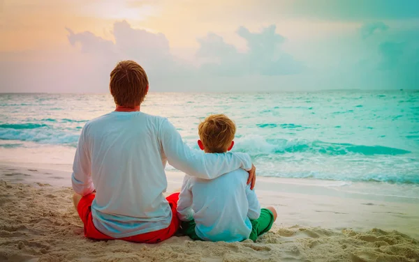 Pai e pequeno filho abraço na praia — Fotografia de Stock