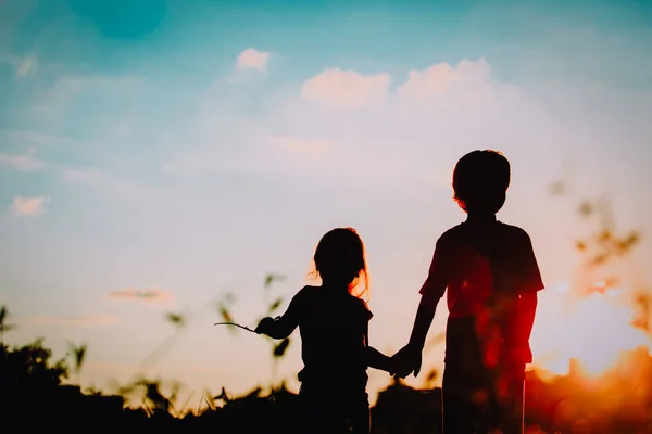 Силуэты мальчиков и девочек держатся за руки на закате — стоковое фото