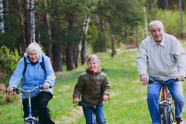 Active senior couple with kid riding bikes in nature — Stock Photo, Image