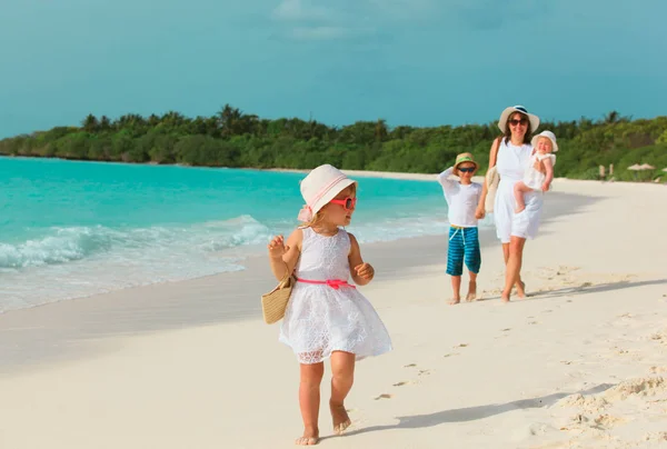 Anne, kız ve erkek kardeş ile sevimli küçük kız sahilde yürümek — Stok fotoğraf