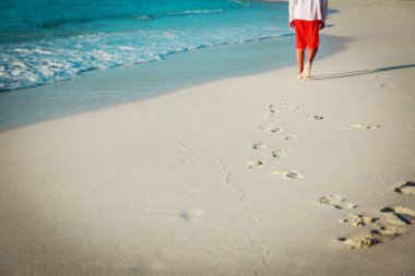 küçük çocuk kuma ayak izi bırakarak Sahilde yürüyüş