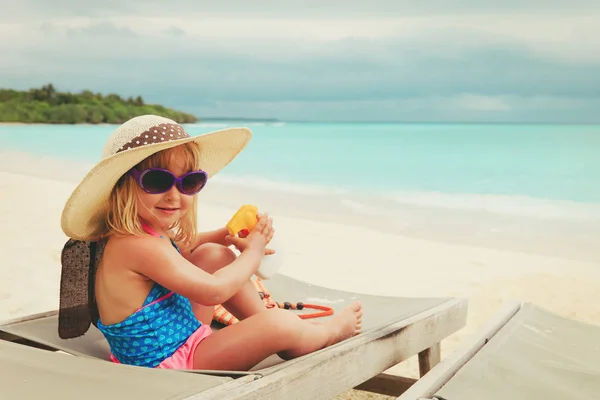 Protección solar - niña con crema solar en la playa —  Fotos de Stock