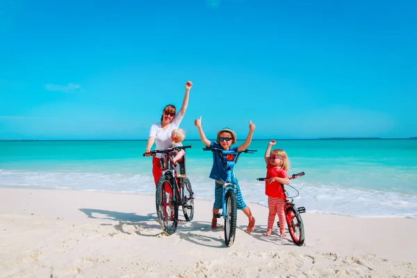 Gelukkig moeder met kinderen fietsen op strand — Stockfoto