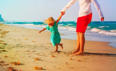 Baba ve küçük kız sahilde oynuyorlar.