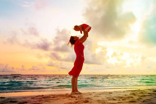 Mutter und kleine Tochter spielen am Strand bei Sonnenuntergang — Stockfoto