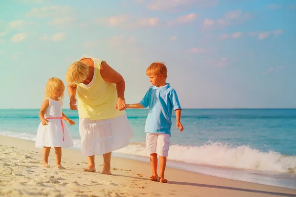 Glad mormor med kids - liten pojke och flicka-vid stranden — Stockfoto