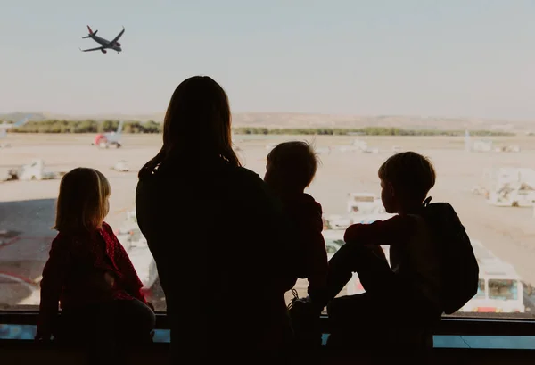 Familia viaje- madre con niños mirando aviones en el aeropuerto — Foto de Stock