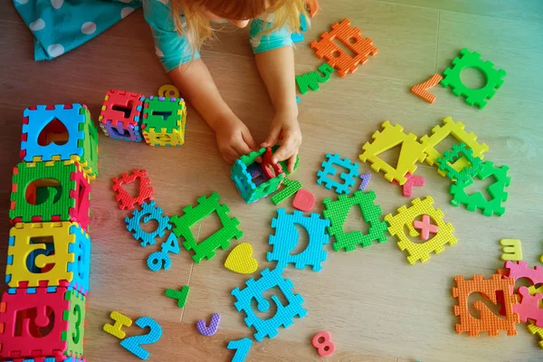 Liten flicka lära sig siffror och former, leka med pussel — Stockfoto