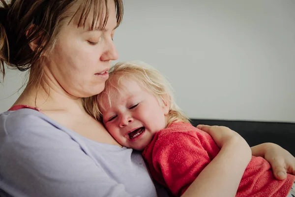 Äiti lohduttaa itkevää pientä vauvaa — kuvapankkivalokuva