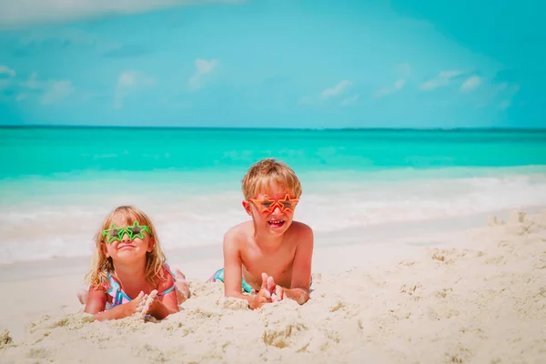 Menino e menina brincam com areia na praia — Fotografia de Stock