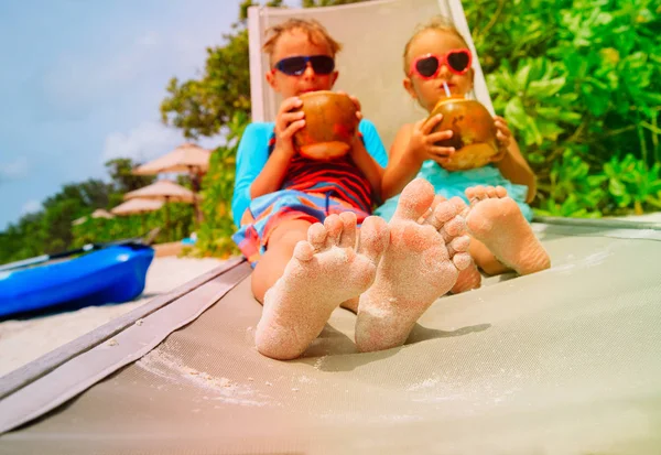 Niño y niña bebiendo coco en la playa, concepto de relax — Foto de Stock