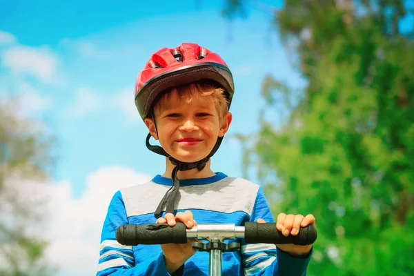 Счастливый мальчик в шлеме катается на скутере — стоковое фото