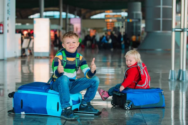 Μικρό αγόρι και κορίτσι wating στο αεροδρόμιο που κάθεται στις βαλίτσες — Φωτογραφία Αρχείου