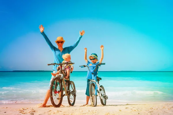 Батько з маленьким сином і дочкою їде на велосипеді на пляжі — стокове фото