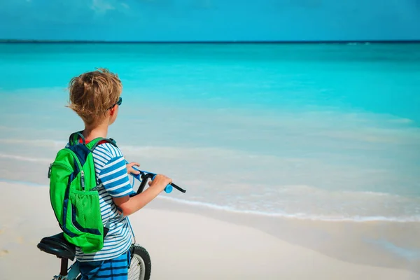 little boy travel ride bike on tropical beach