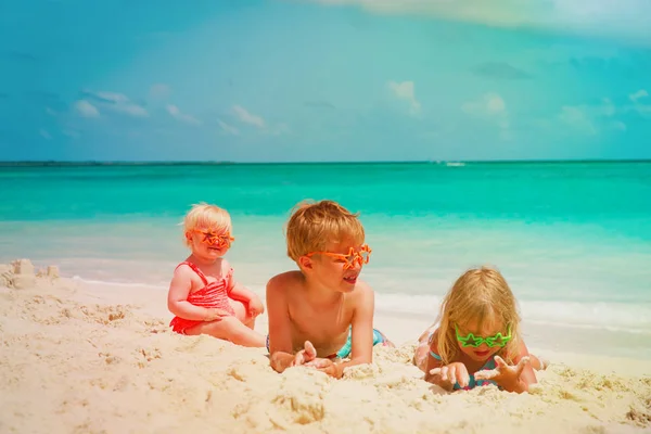 Niños - niño y niñas - jugar con arena en la playa — Foto de Stock
