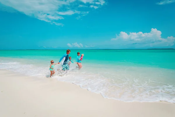 Šťastná rodina s dětmi hrát s vody na pláži — Stock fotografie
