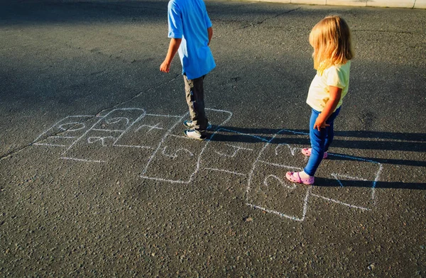 เด็กเล่นฮ็อปสก็อตช์บนสนามเด็กเล่น — ภาพถ่ายสต็อก
