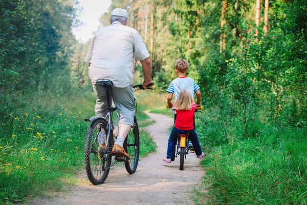Ativo sênior com netos andar de bicicleta na natureza — Fotografia de Stock