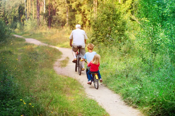 Ativo sênior com netos andar de bicicleta na natureza — Fotografia de Stock