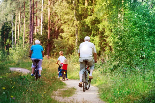active senior grandparents with kids riding bikes in nature