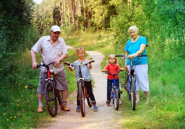 Активна старша пара з дітьми верхи на велосипедах у природі — стокове фото