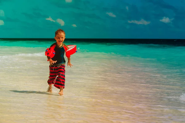 Kleine Jungen laufen Spiel mit Wasser am tropischen Strand — Stockfoto