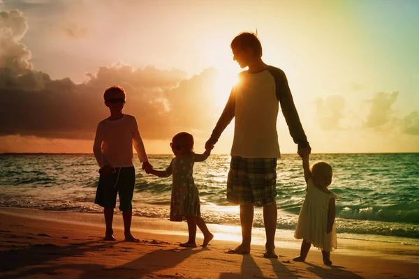 Père avec des enfants marchant sur la plage au coucher du soleil — Photo