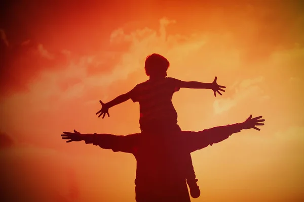 Père et fils jouent sur le ciel couchant — Photo