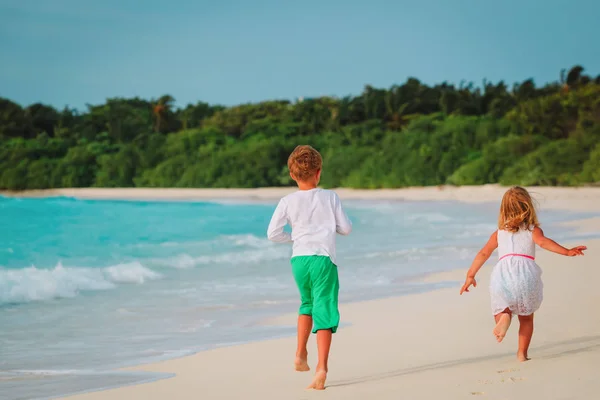 Kleine jongen en meisje lopen op strand — Stockfoto