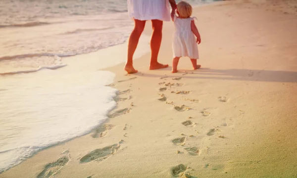 Mutter und Tochter gehen am Strand spazieren und hinterlassen Fußabdrücke im Sand — Stockfoto