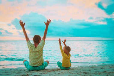 Baba ve oğul eğleniyor günbatımında tropikal plaj keyfini